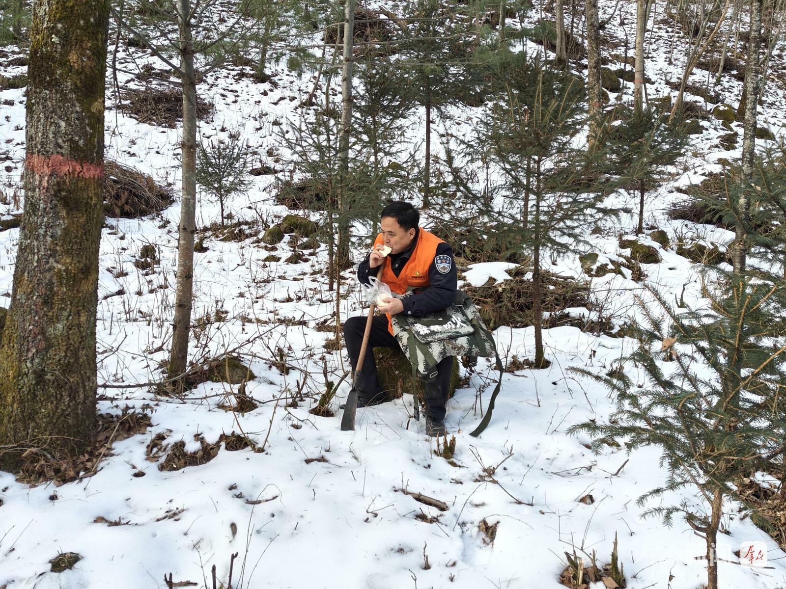 王伟在巡护途中坐在山石上歇脚时,补充体力。.jpg